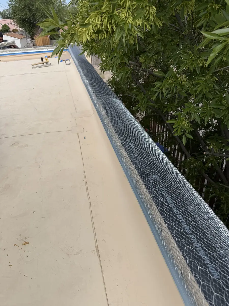 Wire lath wrapped over the full length of a parapet wall beside a flat roof, ready for stucco.