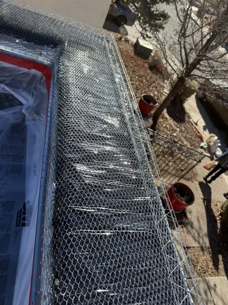 Metal lath fastened over the water barrier membrane along the top of a wall, with the window below masked off in plastic.