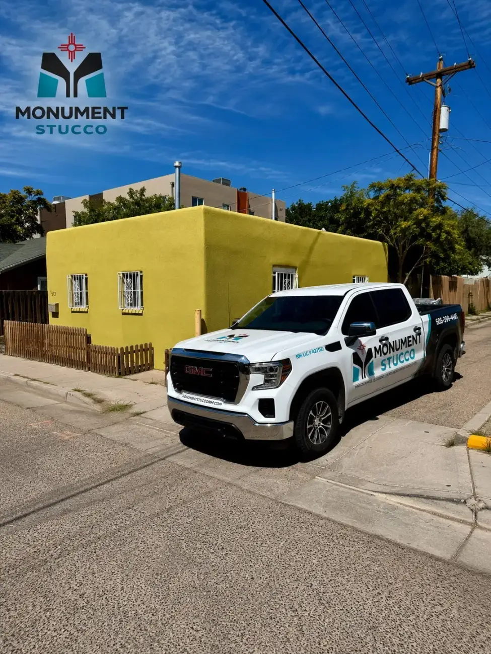 The Monument Stucco pickup truck parked at the curb beside a small Albuquerque house finished in yellow green stucco.