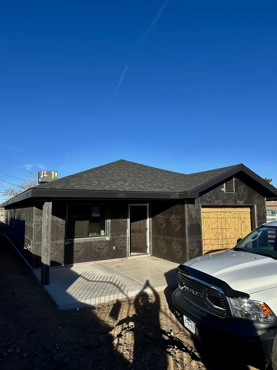 House wrapped in water barrier membrane and metal lath with the garage opening boarded, ready for the first coat of stucco.