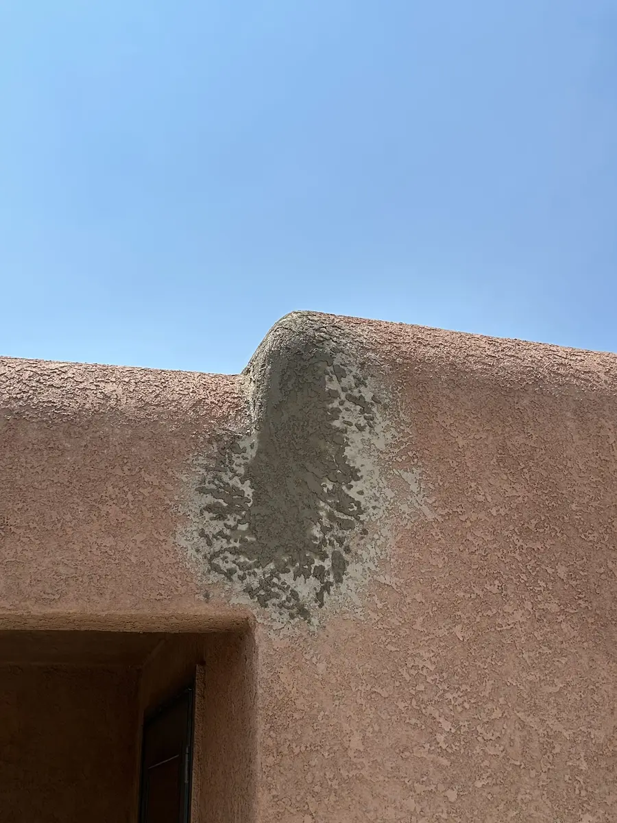 Fresh grey patch material worked into the corner of a terracotta parapet wall.
