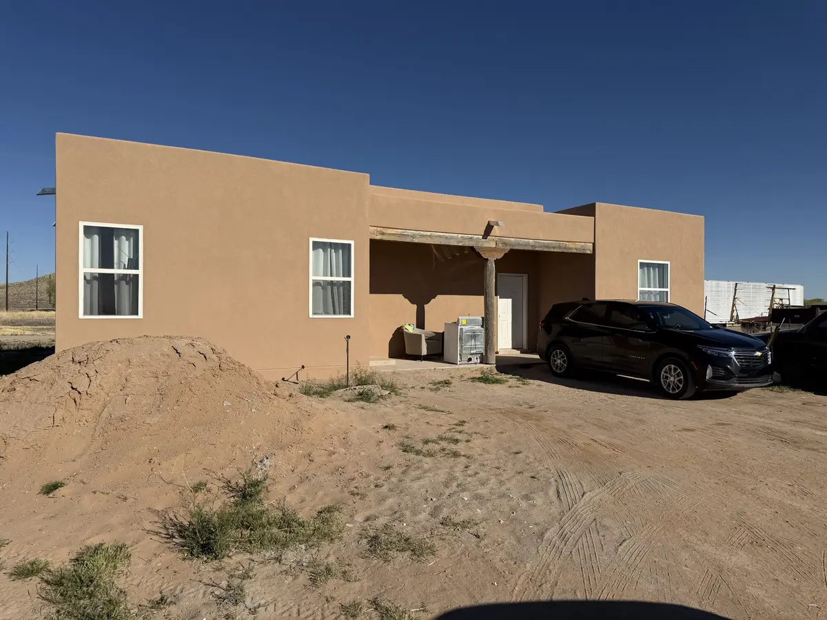 Single story new home finished in salmon colored stucco with white trimmed windows.