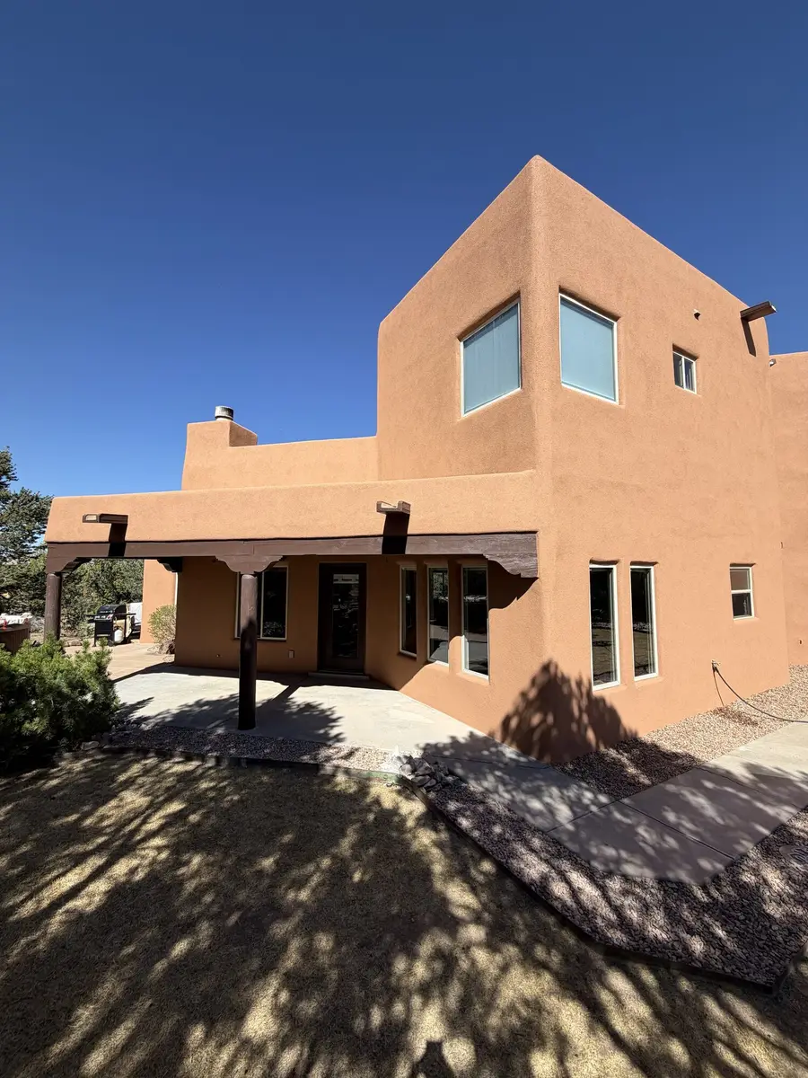 Two story home in terracotta stucco with a covered portal carried on wooden corbels and beams.